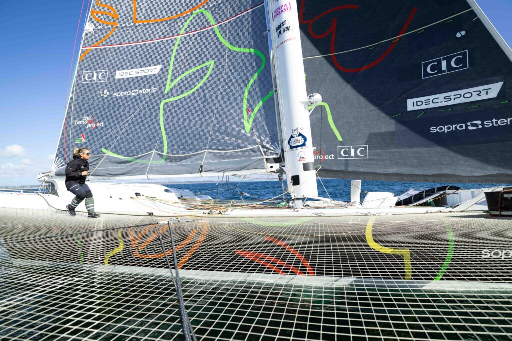 Alexia Barrier en manœuvre sur le filet du maxi-trimaran IDEC SPORT-CIC, voiles aux couleurs du CIC, d'IDEC SPORT et de SOPRA STERIA